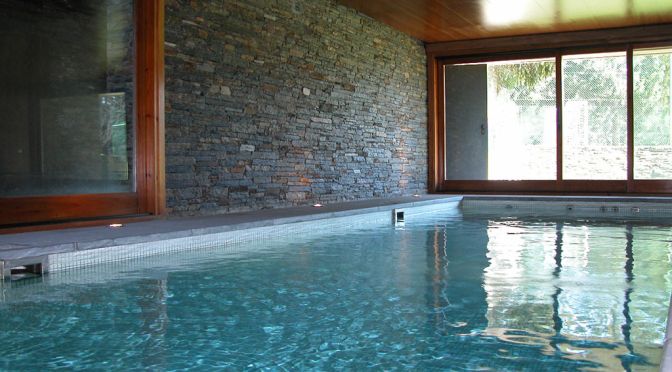 Piscina interior con muro de piedra, proyecto de MA&MA POOL